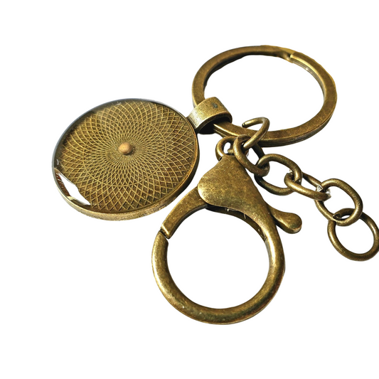 Close-up image of a large bronze keychain featuring a round pendant with a single real mustard seed sealed in clear resin at the center. The pendant is encased in a vintage bronze bezel, giving it a warm, rustic appearance. Attached to a sturdy key ring, the keychain also includes a large bronze lobster clasp for smooth, secure attachment to keys, bags, or gear. A meaningful, faith-based accessory with minimalist design.