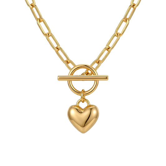 A professional product image of a polished 14k gold-plated paperclip chain necklace hanging in a symmetrical V-shape against a pure white background, featuring a center toggle clasp closure with a dangling puffed heart charm.