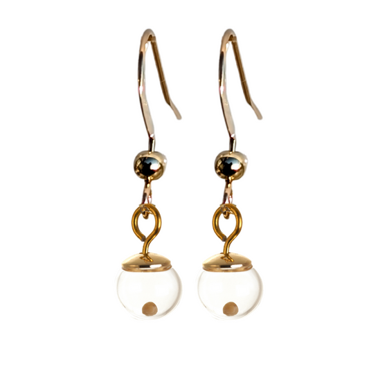 Close-up of a Pair of gold-filled mustard seed earrings featuring shepherd hooks. Each earring has a tiny pendant made from an 8mm hand-blown glass globe containing a single real mustard seed, capped with a polished 14K gold-filled cap, and is suspended from a handmade 3mm loop.