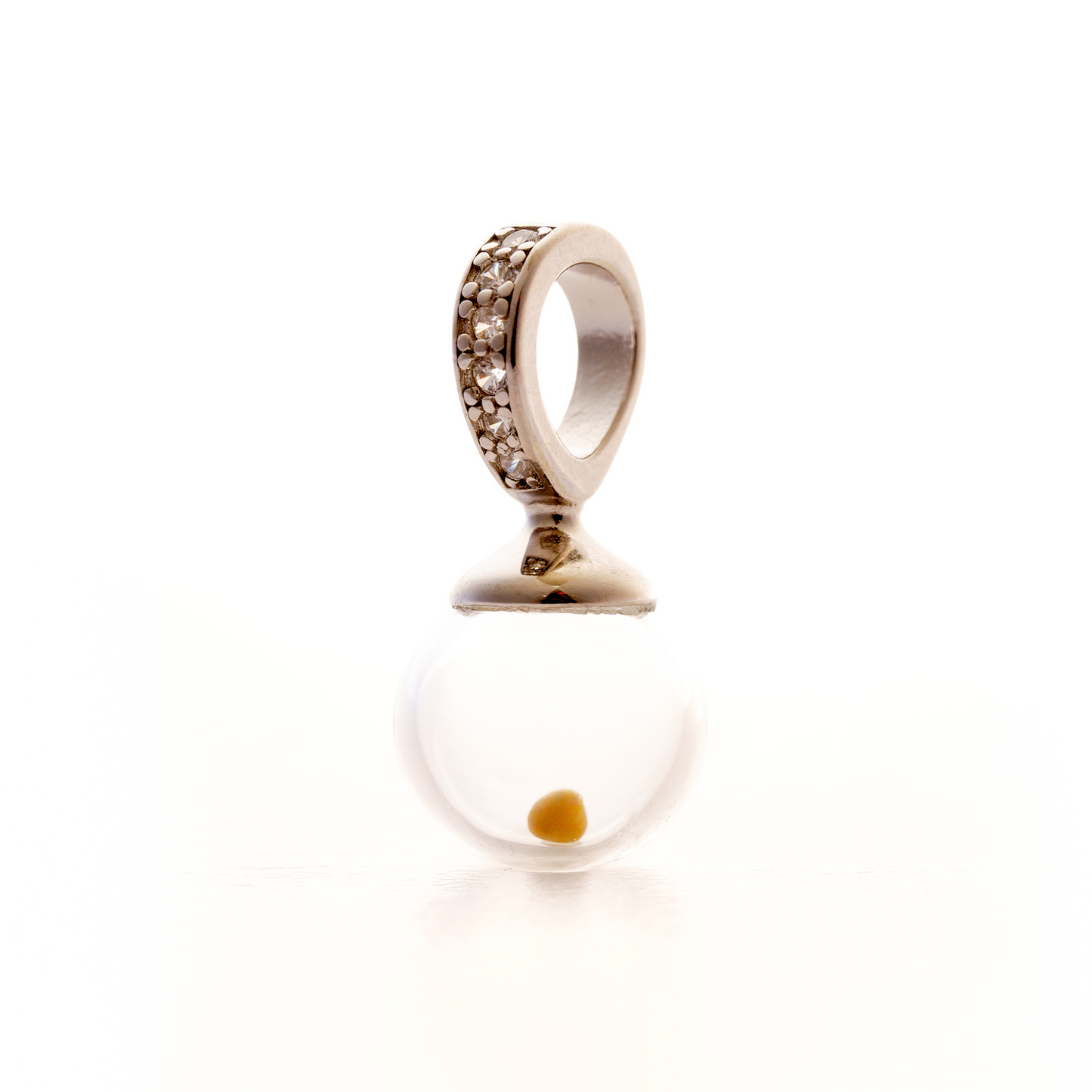 Close-up image of a crystal-accented mustard seed charm featuring a real mustard seed sealed inside a 10mm clear hand-blown glass globe. The globe is topped with a smooth silver cap and attached to a wide bail adorned with a row of small, sparkling crystals. The charm is photographed against a bright white background, highlighting its delicate and elegant design.