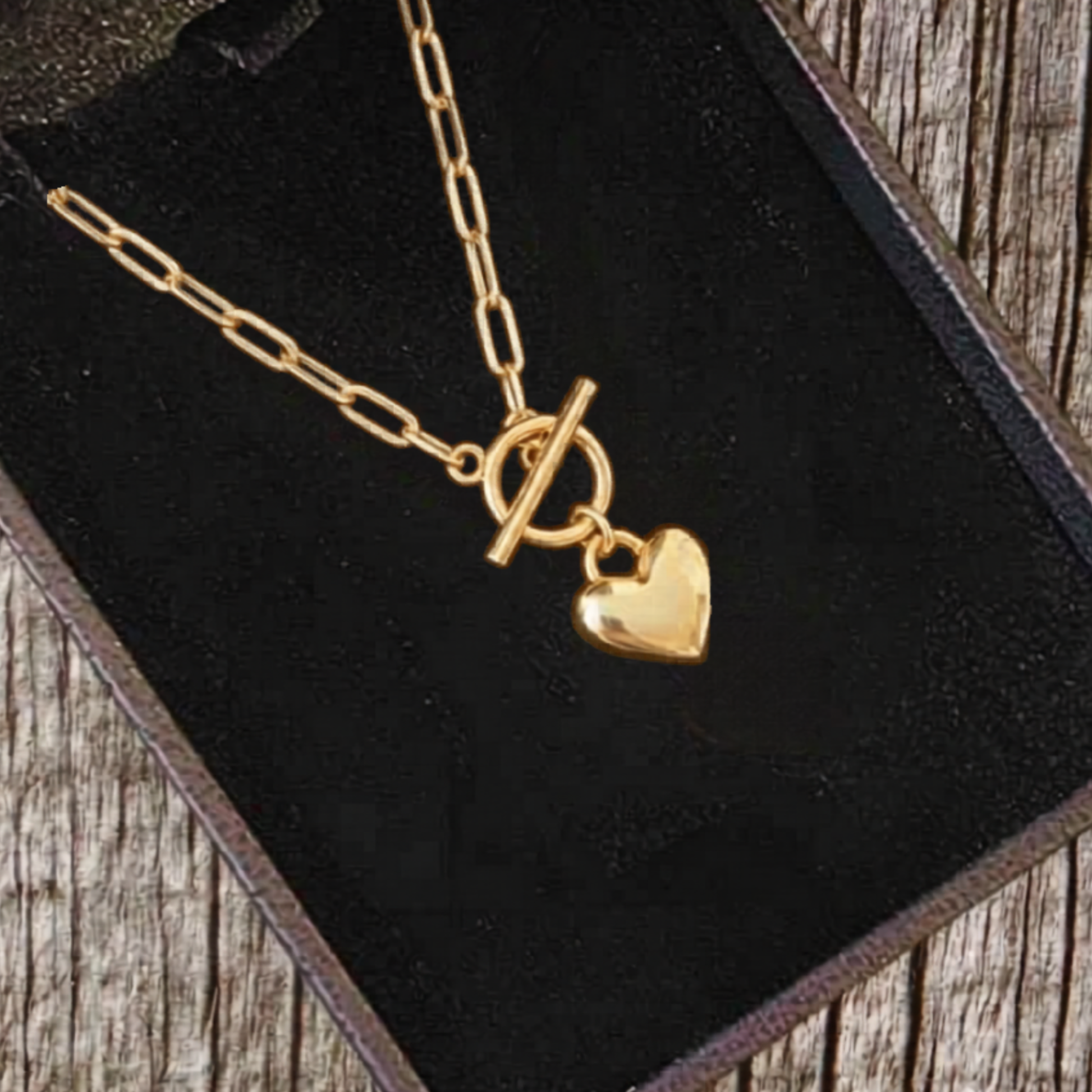 Gold necklace with a heart pendant on a black velvet surface